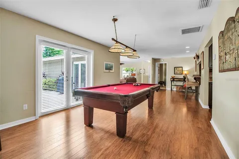 a room with pool table windows and wooden floor