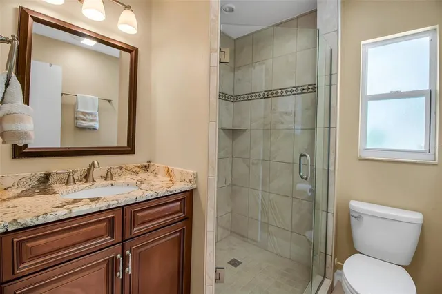 a bathroom with a granite countertop toilet sink shower and mirror