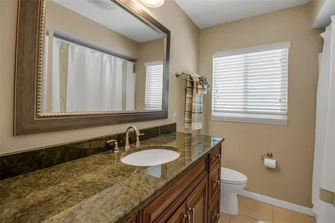 a bathroom with a granite countertop sink toilet a mirror and a window