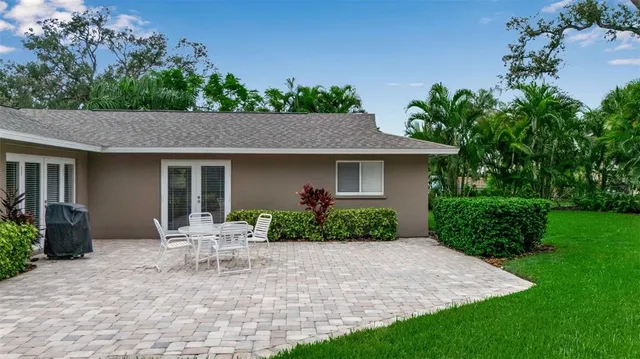 a patio with a table and chairs and potted plants
