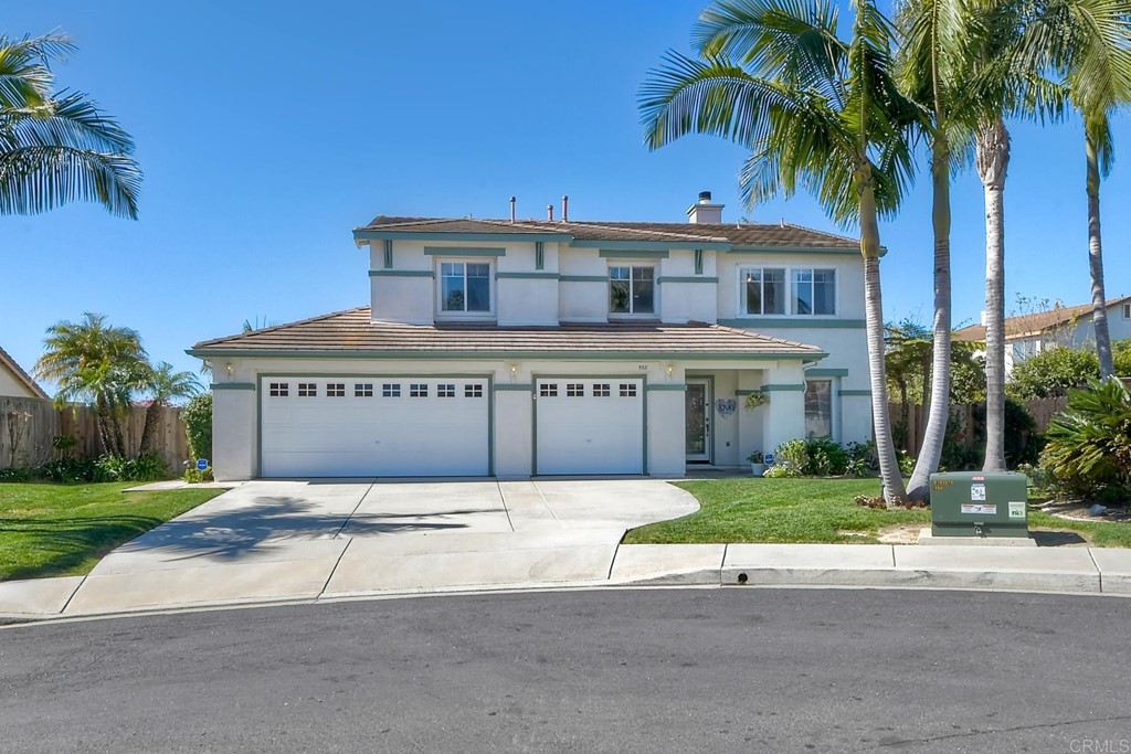 a view of a house with a yard and palm trees