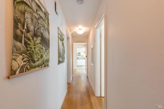 a view of a hallway with wooden floor and a bathroom