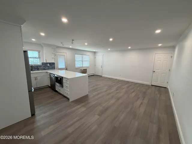 a large kitchen with stainless steel appliances granite countertop a large counter top a sink and a refrigerator