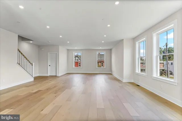 a view of an empty room with a window and wooden floor