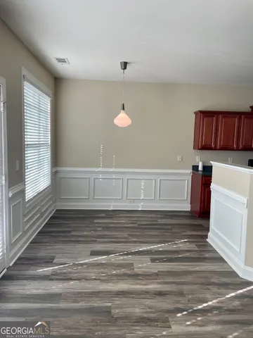 a view of kitchen and empty room with wooden floor
