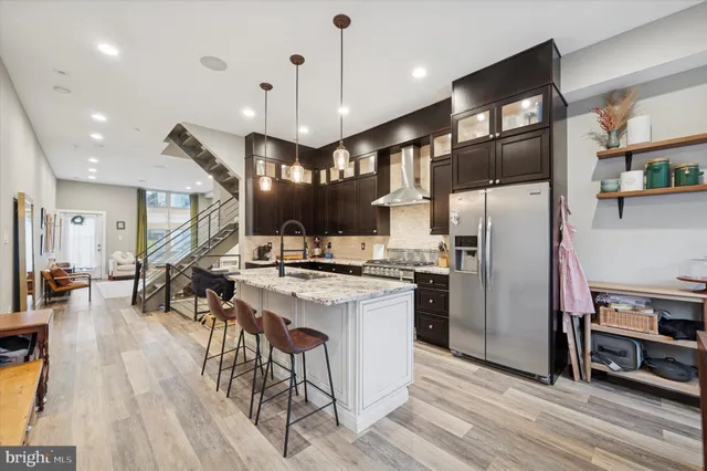 a kitchen with stainless steel appliances a refrigerator a stove a sink a dining table and chairs with wooden floor