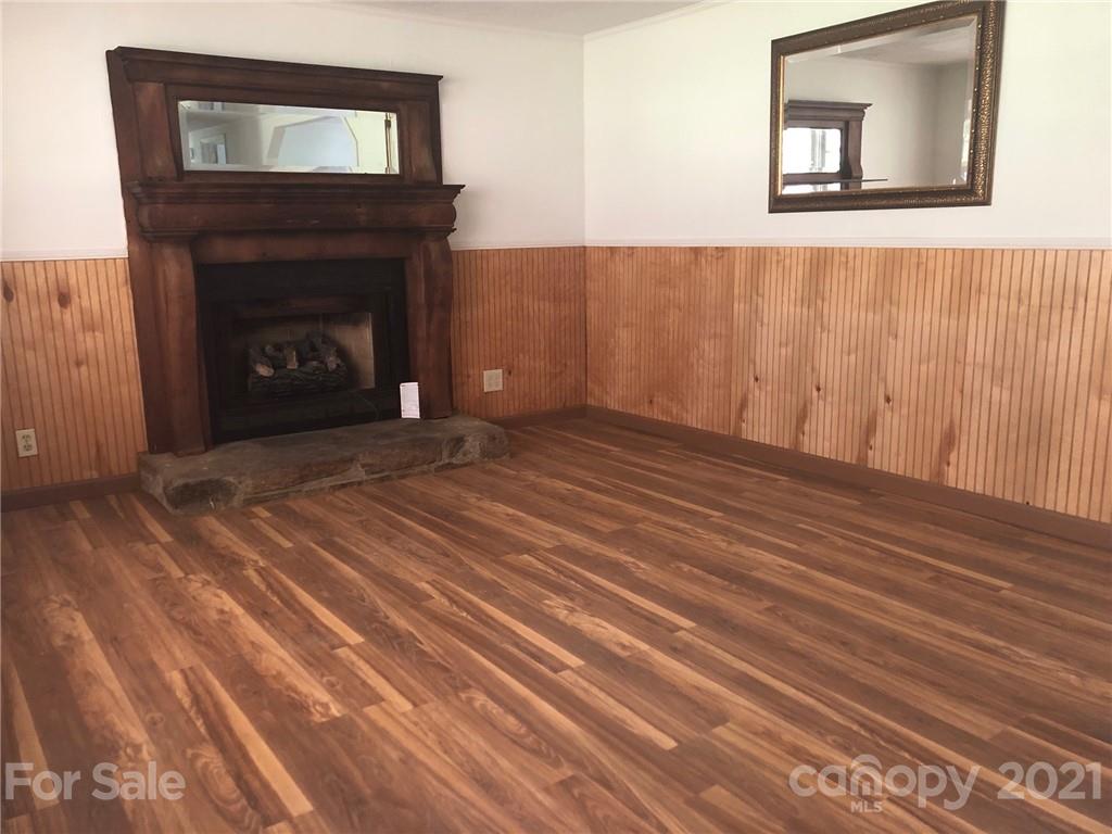 289 Long Branch Road Clyde, NC 28721 - Photo 10 of 44 a view of an empty room with wooden floor and a fireplace