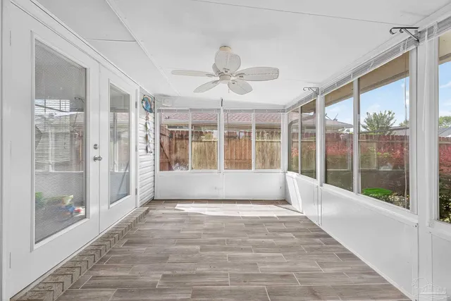 a view of an empty room with a window and chandelier fan