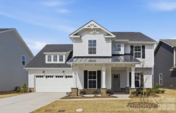 a front view of a house with yard and parking
