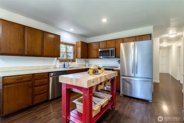 a kitchen with stainless steel appliances granite countertop a refrigerator a sink dishwasher a stove with wooden cabinets and floors