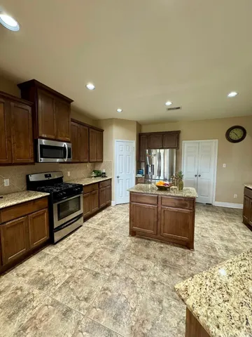 a large kitchen with kitchen island granite countertop a sink and stainless steel appliances