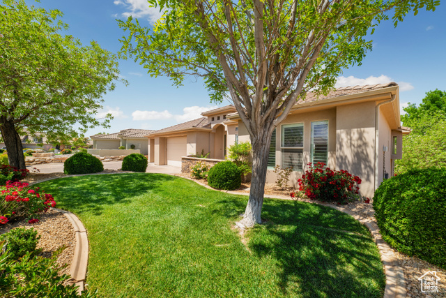 2996 Limestone Drive St. George, UT 84790 - Photo 1 of 1 View of front of property featuring driveway, a tile roof, a garage, stucco siding, and a front lawn