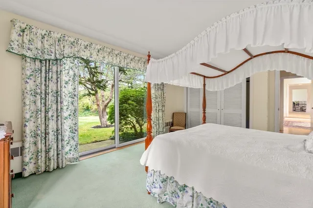 a large white bed sitting in a bedroom next to a window