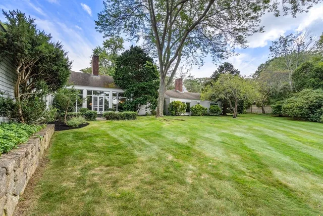 a view of a house with a big yard and large trees