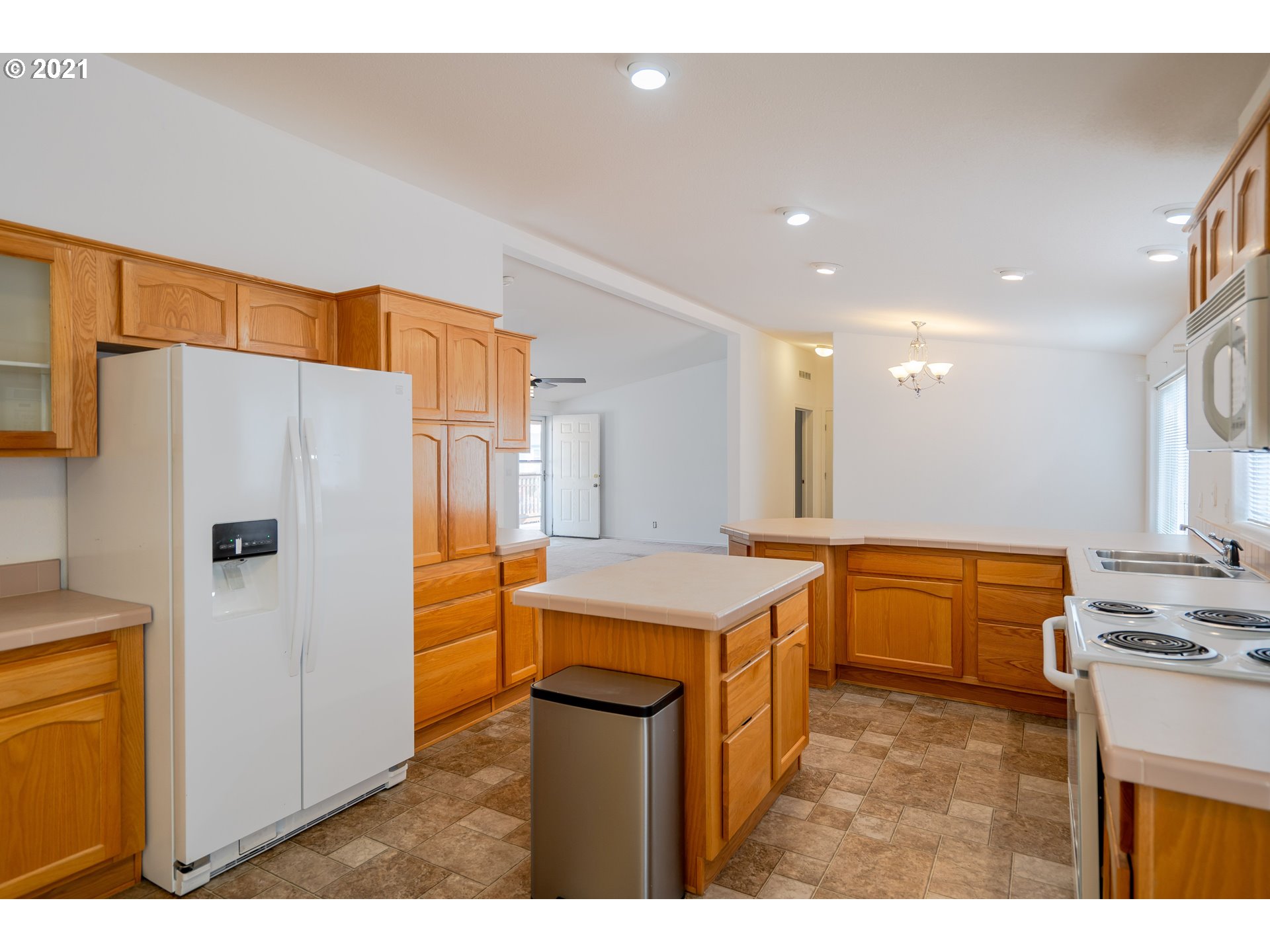 2525 Maia Loop Springfield, OR 97477 - Photo 13 of 27 a kitchen with a refrigerator a sink dishwasher with a dining table and chairs