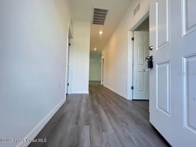 a view of a hallway with wooden floor and staircase
