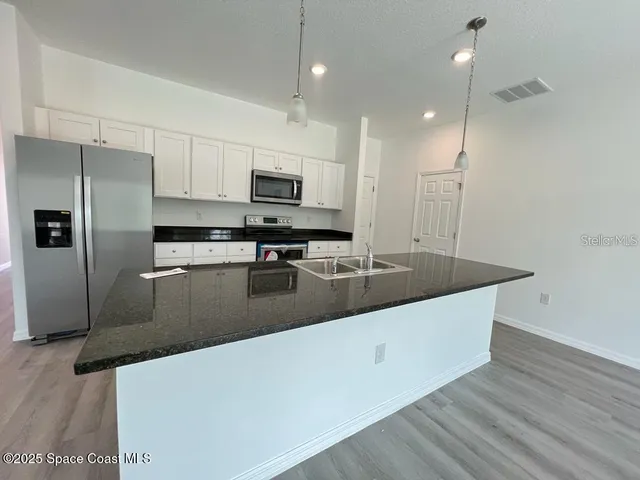 a kitchen with stainless steel appliances granite countertop a sink a stove and a refrigerator