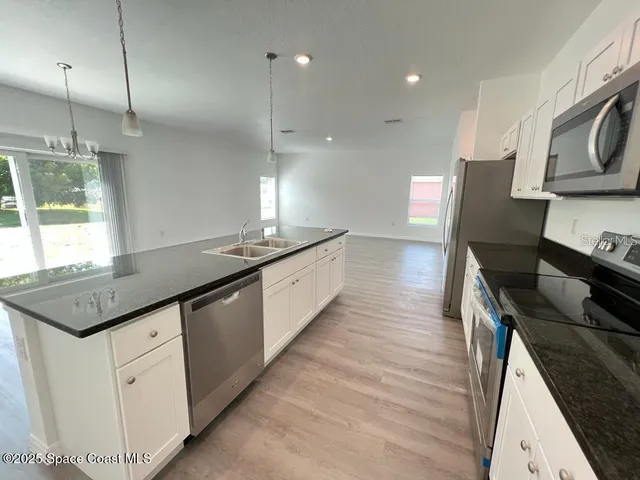 a kitchen with stainless steel appliances granite countertop a sink a stove and a wooden floors