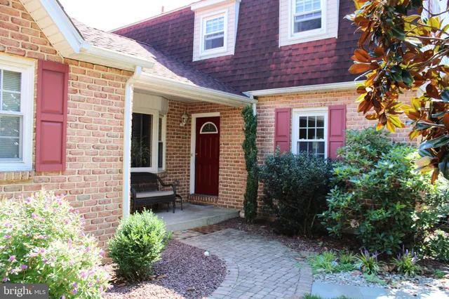 a view of a brick house with plants and a lawn chairs