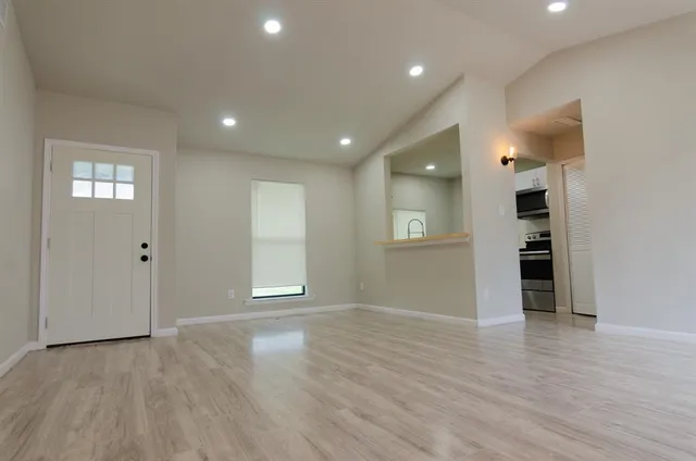 a view of an empty room with wooden floor and a window
