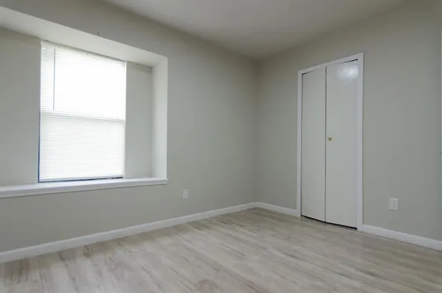 an empty room with wooden floor and windows
