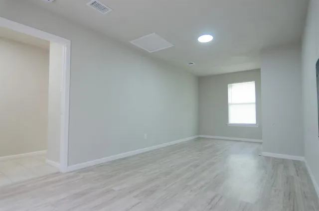 an empty room with wooden floor and windows