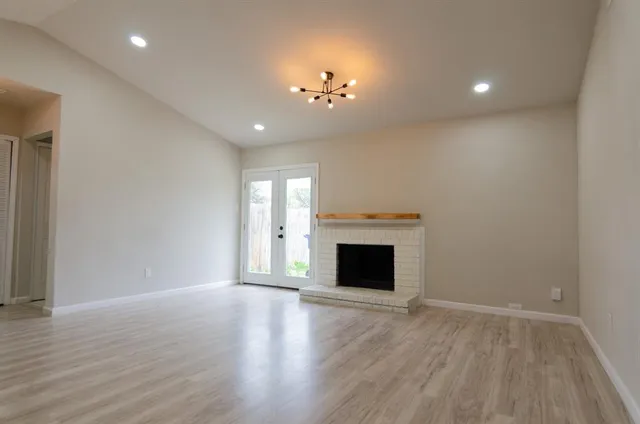 a view of an empty room with wooden floor fireplace and a window