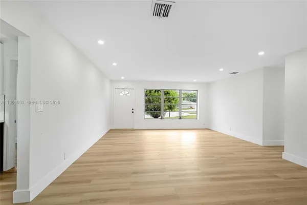 a view of an empty room with wooden floor and a window