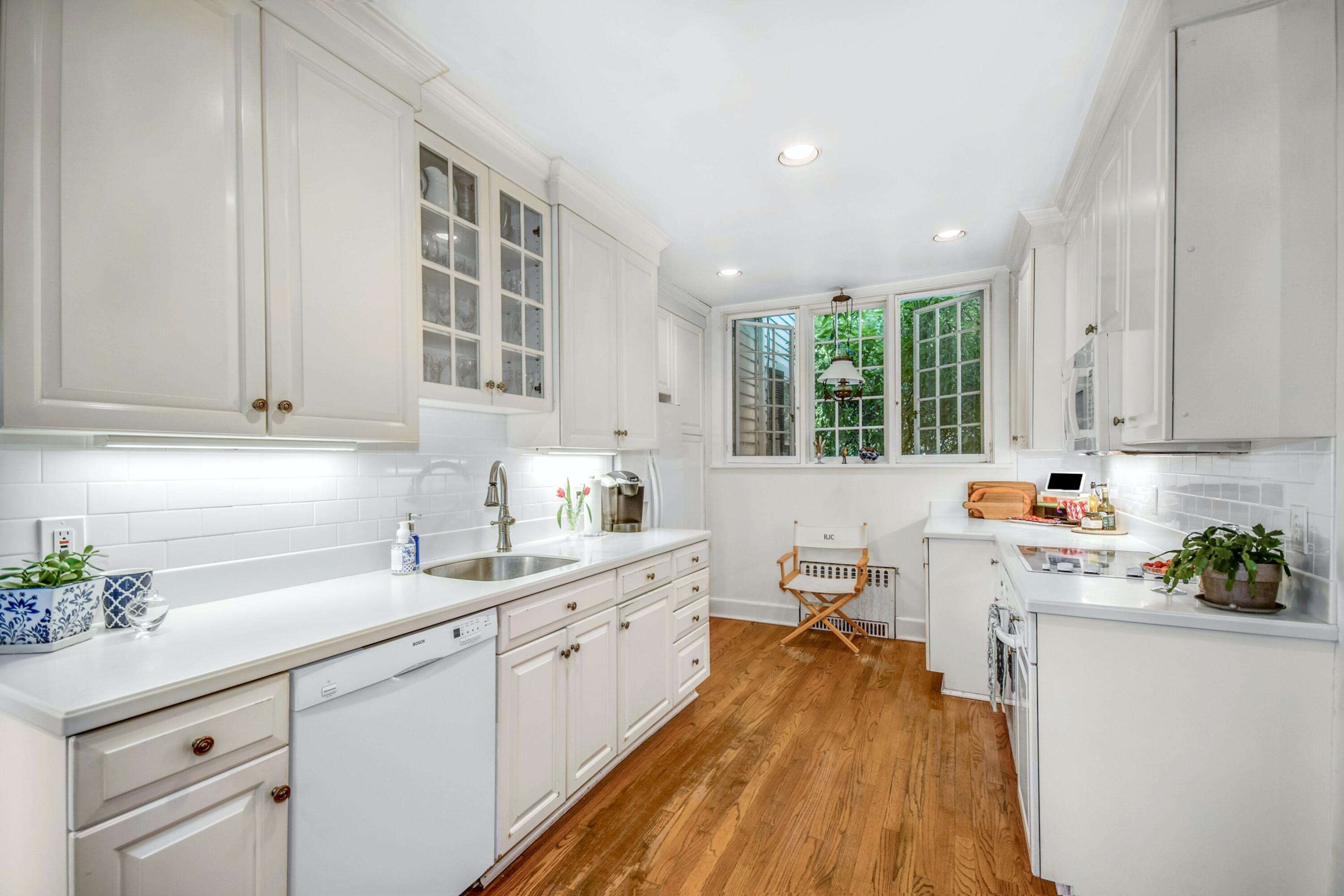 162 Marshall Ridge Road New Canaan, CT 06840 - Photo 12 of 29 a kitchen with a sink dishwasher stove and white cabinets with wooden floor
