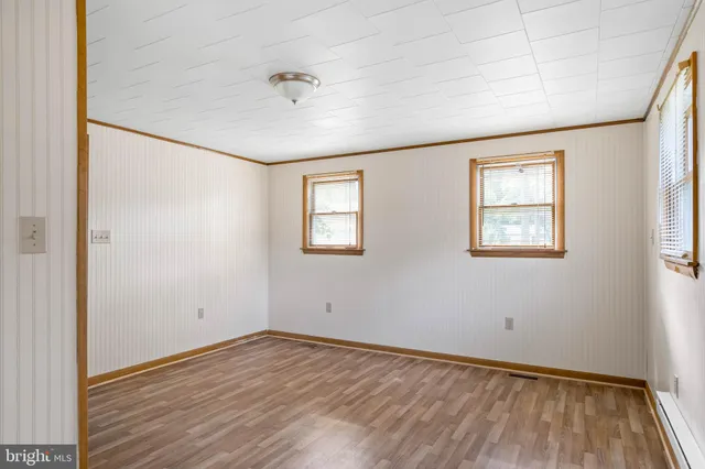an empty room with wooden floor chandelier fan and windows