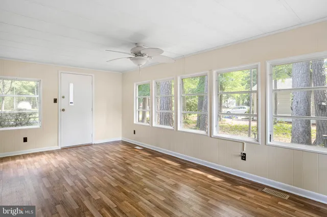 a view of an empty room with a window and wooden floor