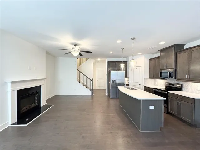 a large white kitchen with stainless steel appliances kitchen island a stove a sink a refrigerator and a fireplace