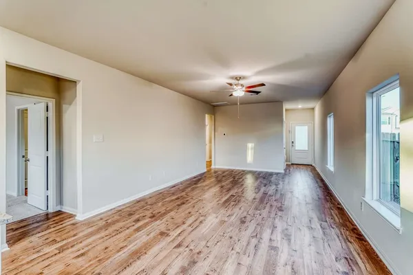 a view of an empty room with wooden floor and a window