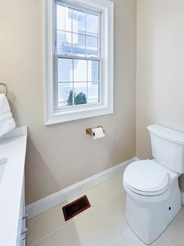 a white toilet sitting next to a window in a bathroom