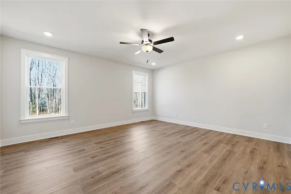 an empty room with wooden floor and windows