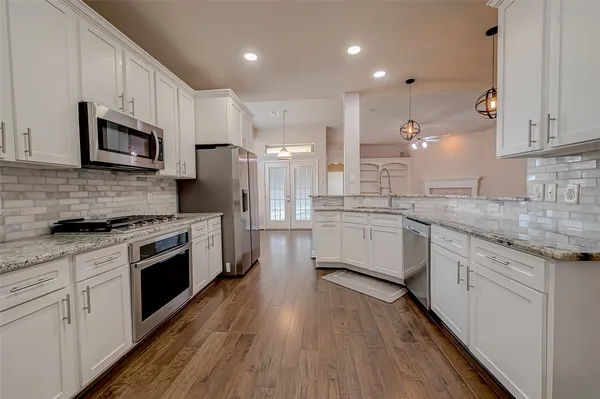 a large kitchen with stainless steel appliances granite countertop a large stove a sink dishwasher and a microwave oven with wooden floor