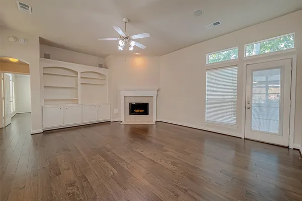 an empty room with wooden floor chandelier and windows