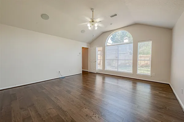 an empty room with wooden floor chandelier and windows
