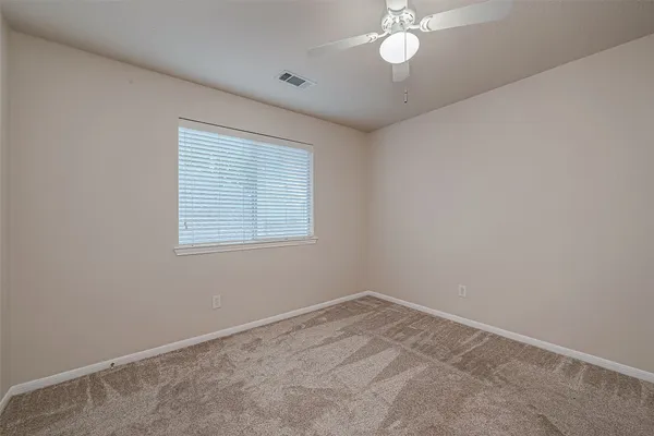 an empty room with a window and a fan