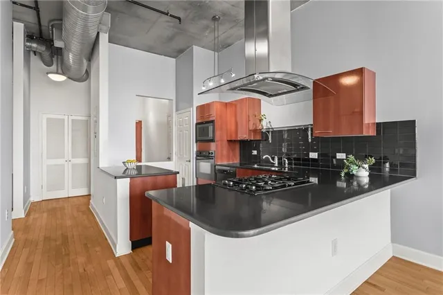 a kitchen with stainless steel appliances granite countertop a sink dishwasher a stove a dining table and chairs with wooden floor