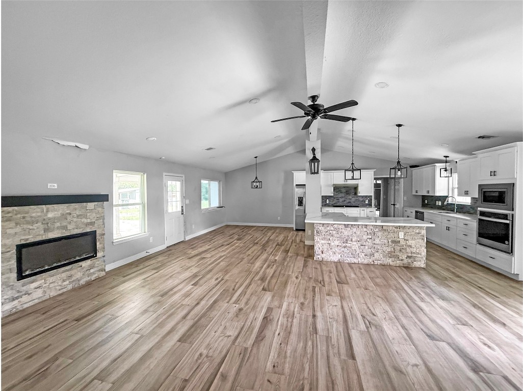 3706 Roberts Boulevard Baytown, TX 77521 - Photo 7 of 22 a large kitchen with kitchen island a stove a sink dishwasher and a fireplace with wooden floor