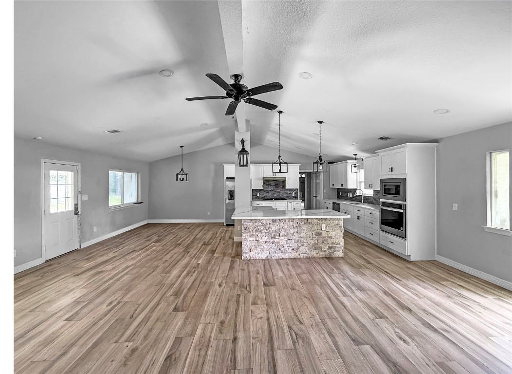 3706 Roberts Boulevard Baytown, TX 77521 - Photo 9 of 22 a large kitchen with kitchen island a stove a sink dishwasher a refrigerator and white cabinets with wooden floor