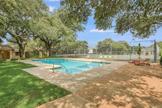 a view of a tennis ground with a large trees