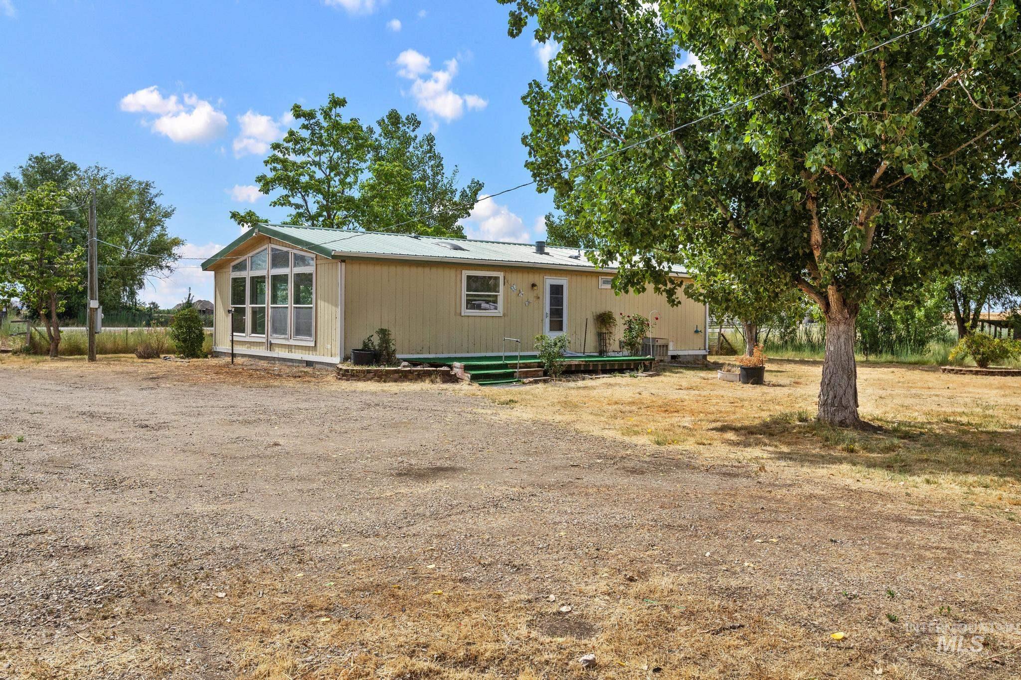 3680 South Mill Road Emmett, ID 83617 - Photo 2 of 38 Single-story residence featuring a sunroom addition with multiple windows, a light-colored siding exterior, and a green metal roof