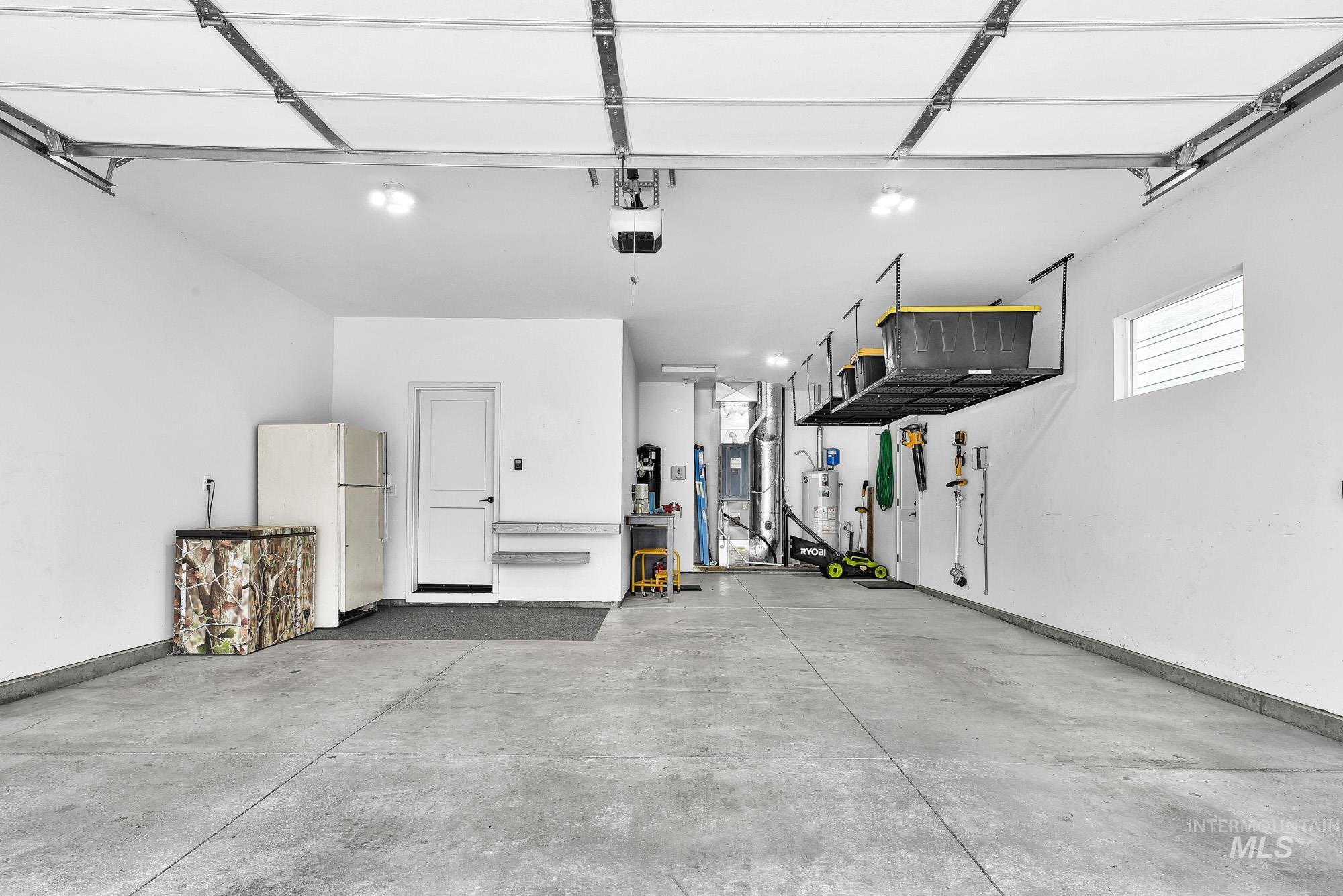 5676 East Zaffre Ridge Street Boise, ID 83716 - Photo 44 of 50 Spacious garage featuring a concrete floor, bright overhead lighting, a white pedestrian door, and a horizontal window