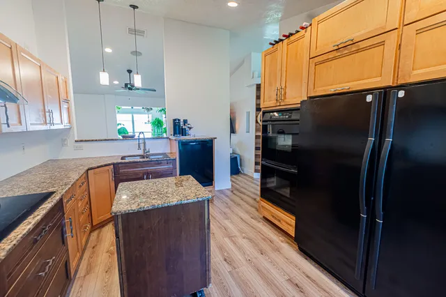 a kitchen with stainless steel appliances granite countertop a refrigerator a sink and a stove