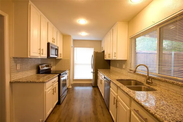 a kitchen with stainless steel appliances granite countertop a sink a stove top oven a counter space and cabinets