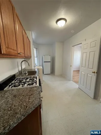 a kitchen with granite countertop a sink stove and refrigerator