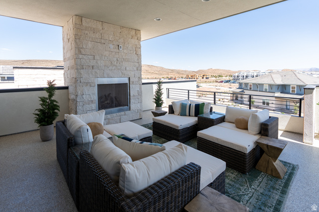 Expansive covered balcony featuring a stone-clad fireplace and durable flooring