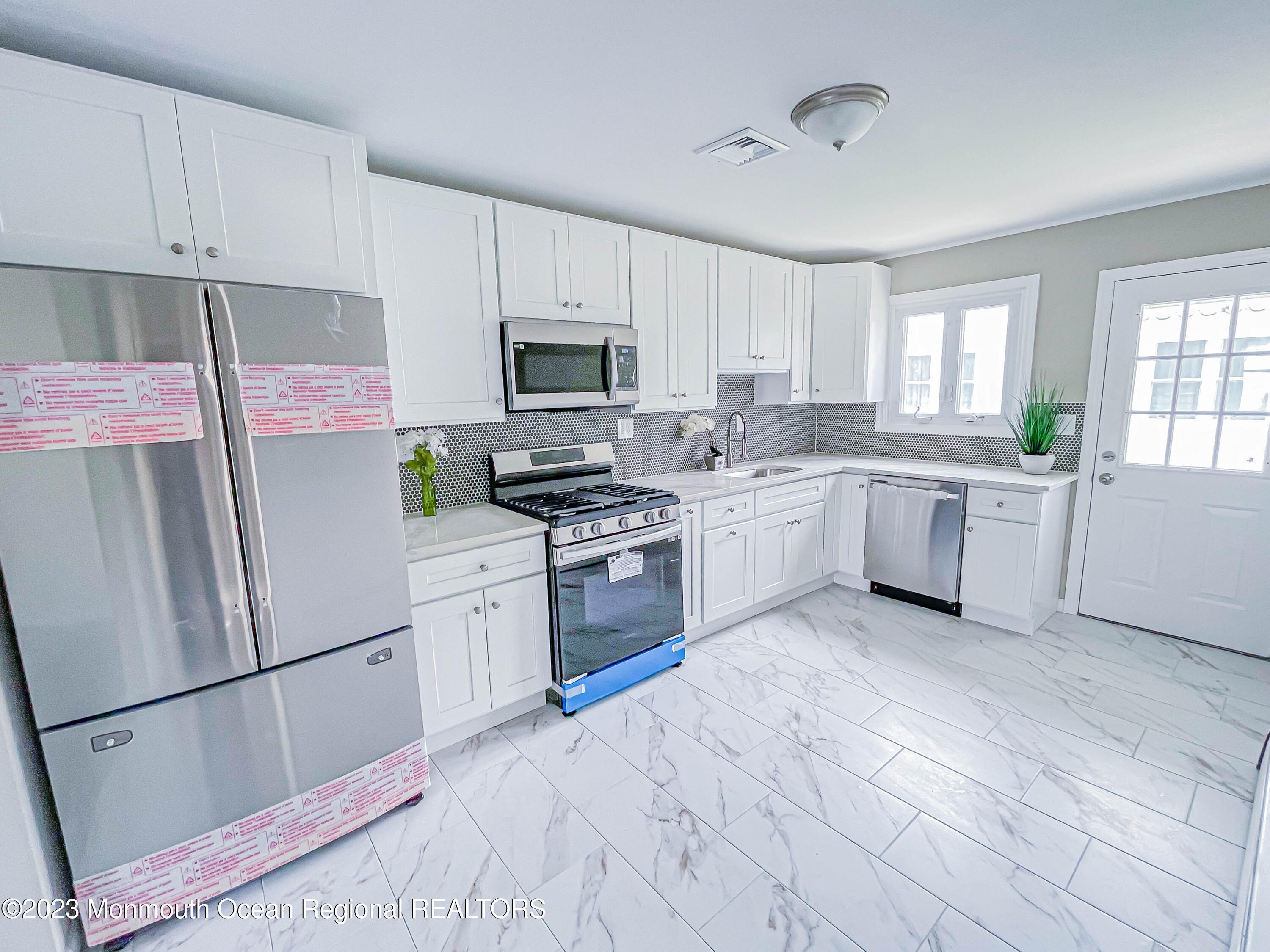 a kitchen with white cabinets stainless steel appliances and window